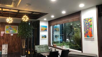A modern interior with a reception desk, seating area, and artwork on the walls.