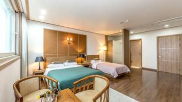 A hotel room with a large bed, two bedside tables, a desk with a chair, and a wardrobe.
