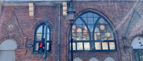 Un edificio de varios pisos de ladrillo con ventanas arqueadas y una señal visible que dice