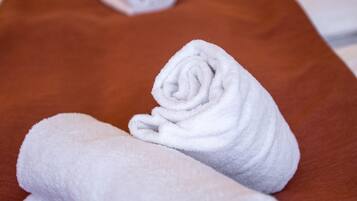 Ein Massagetisch mit zwei aufgerollten weißen Handtüchern und einem braunen Handtuch.