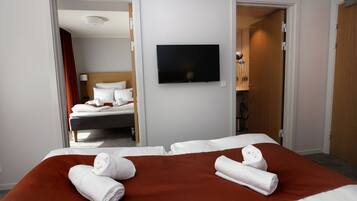 Habitación de hotel con cama, televisor y baño visible a través de una puerta abierta.