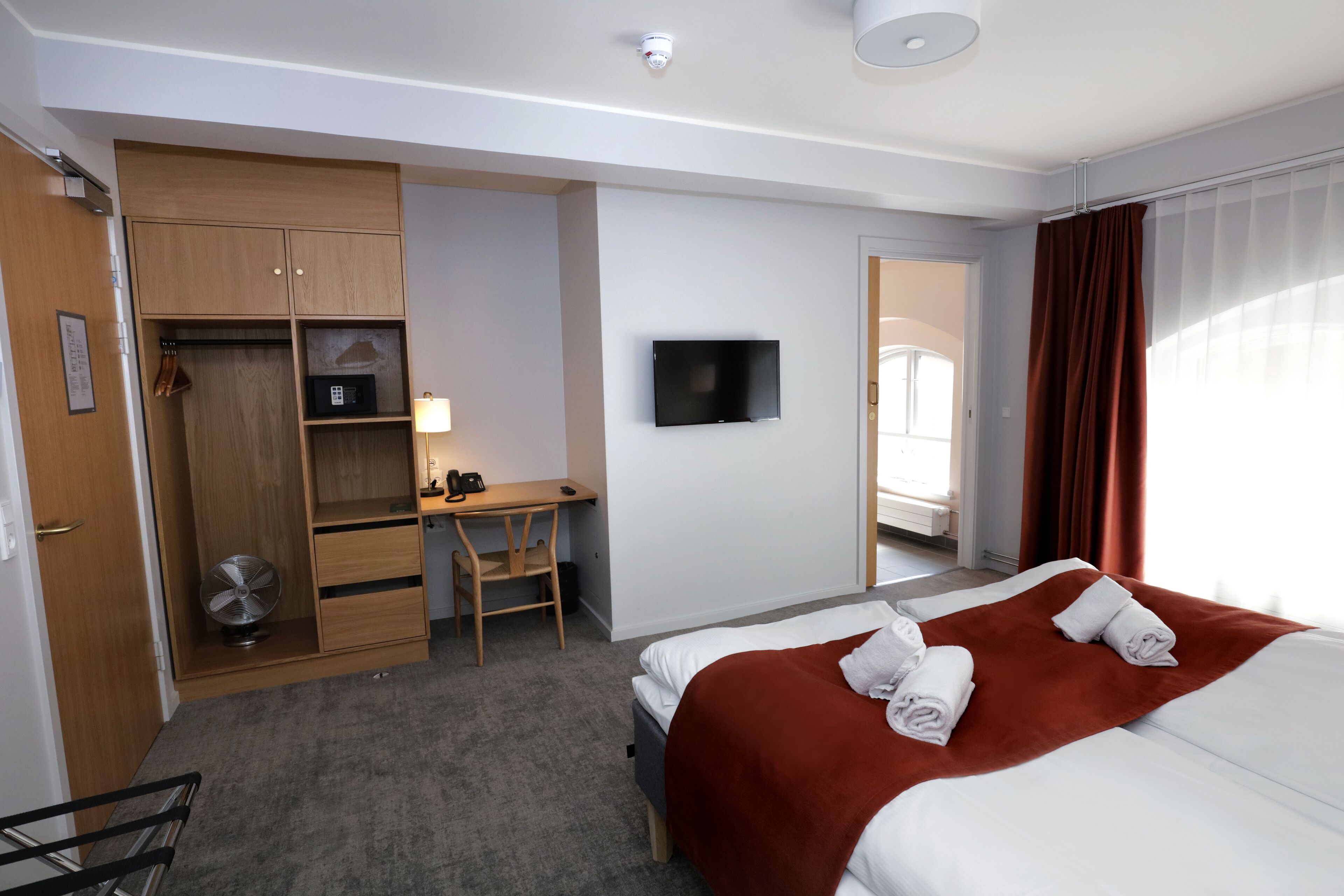Een hotelkamer met een bed, een bureau, een stoel, een kledingkast en een televisie.