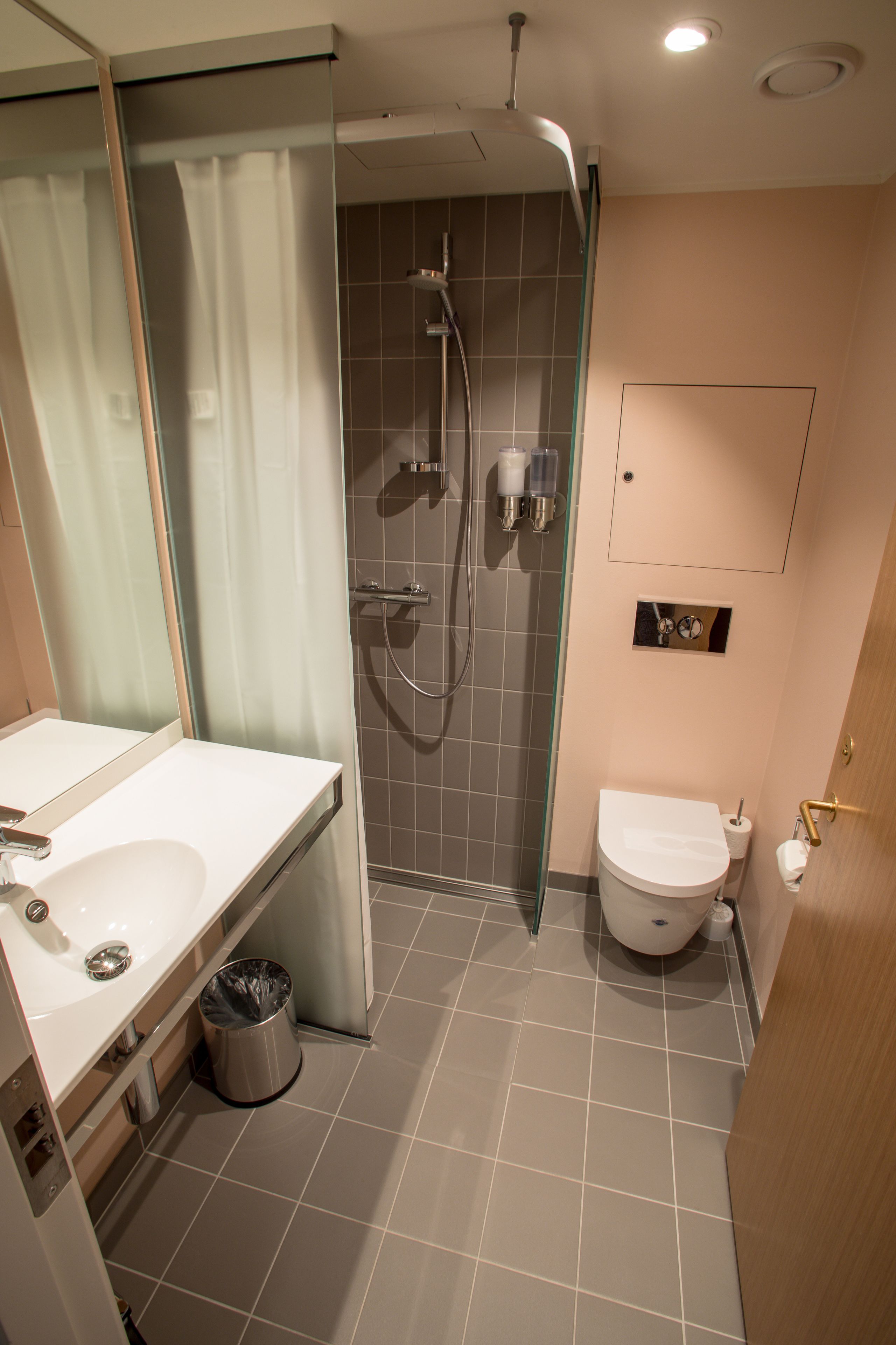 A modern bathroom with a glass-enclosed shower, a white sink, and a toilet.