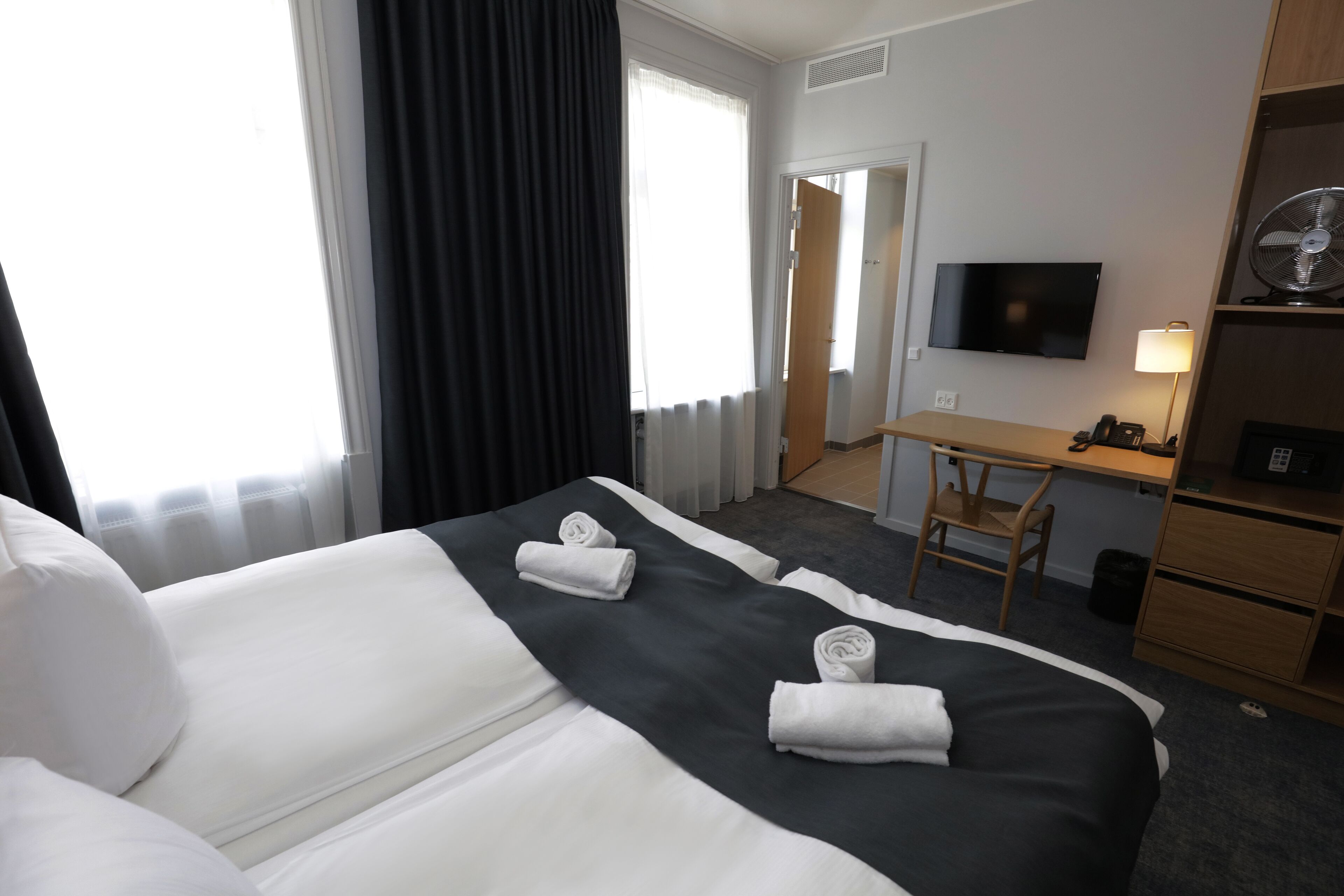 Una habitación de hotel con dos camas, un escritorio, una silla, un televisor y una lámpara.