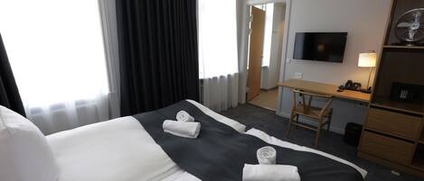 Una habitación de hotel con dos camas, un escritorio, una silla, un televisor y una lámpara.