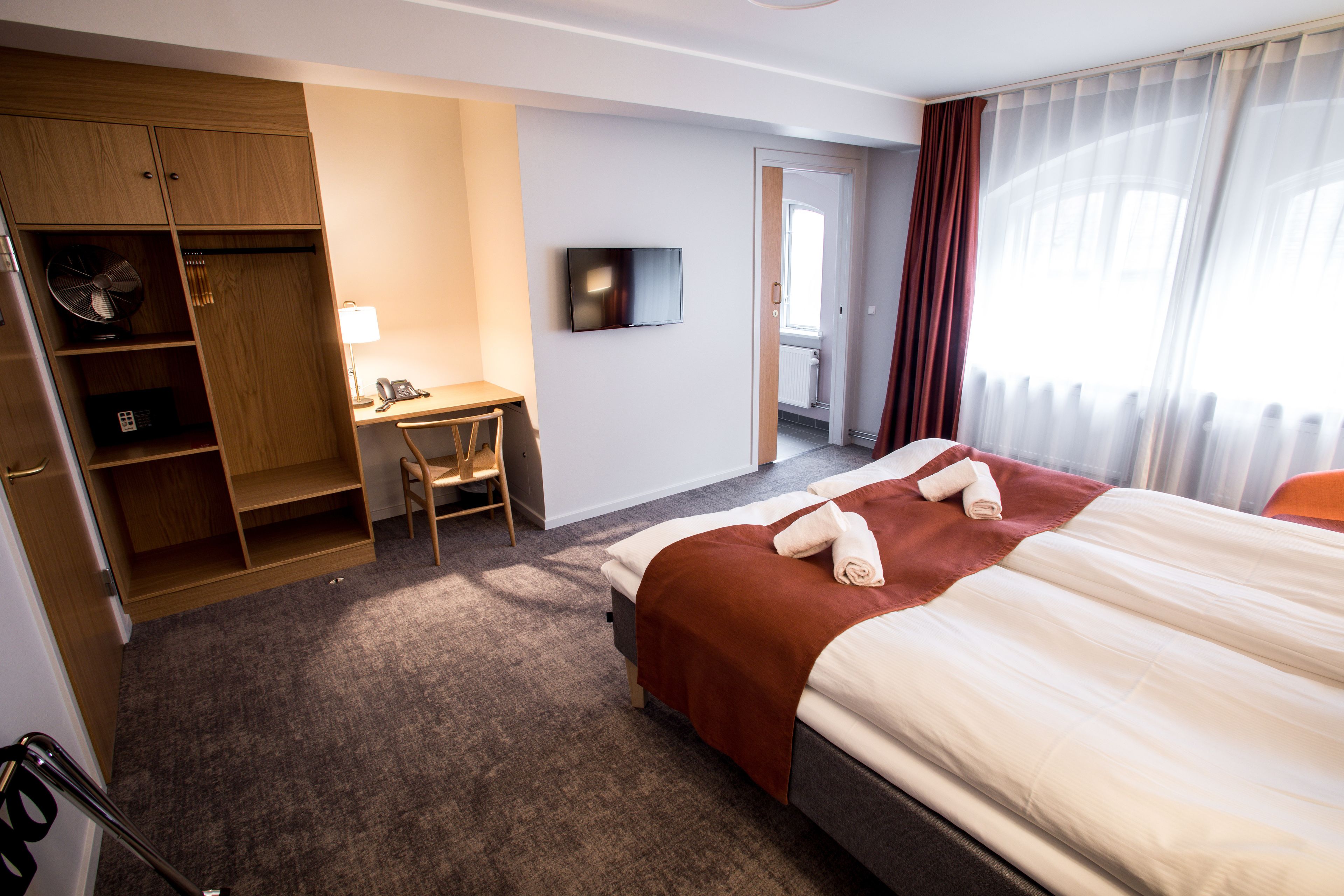 Een hotelkamer met een bed, een bureau, een stoel, een televisie en een kledingkast.