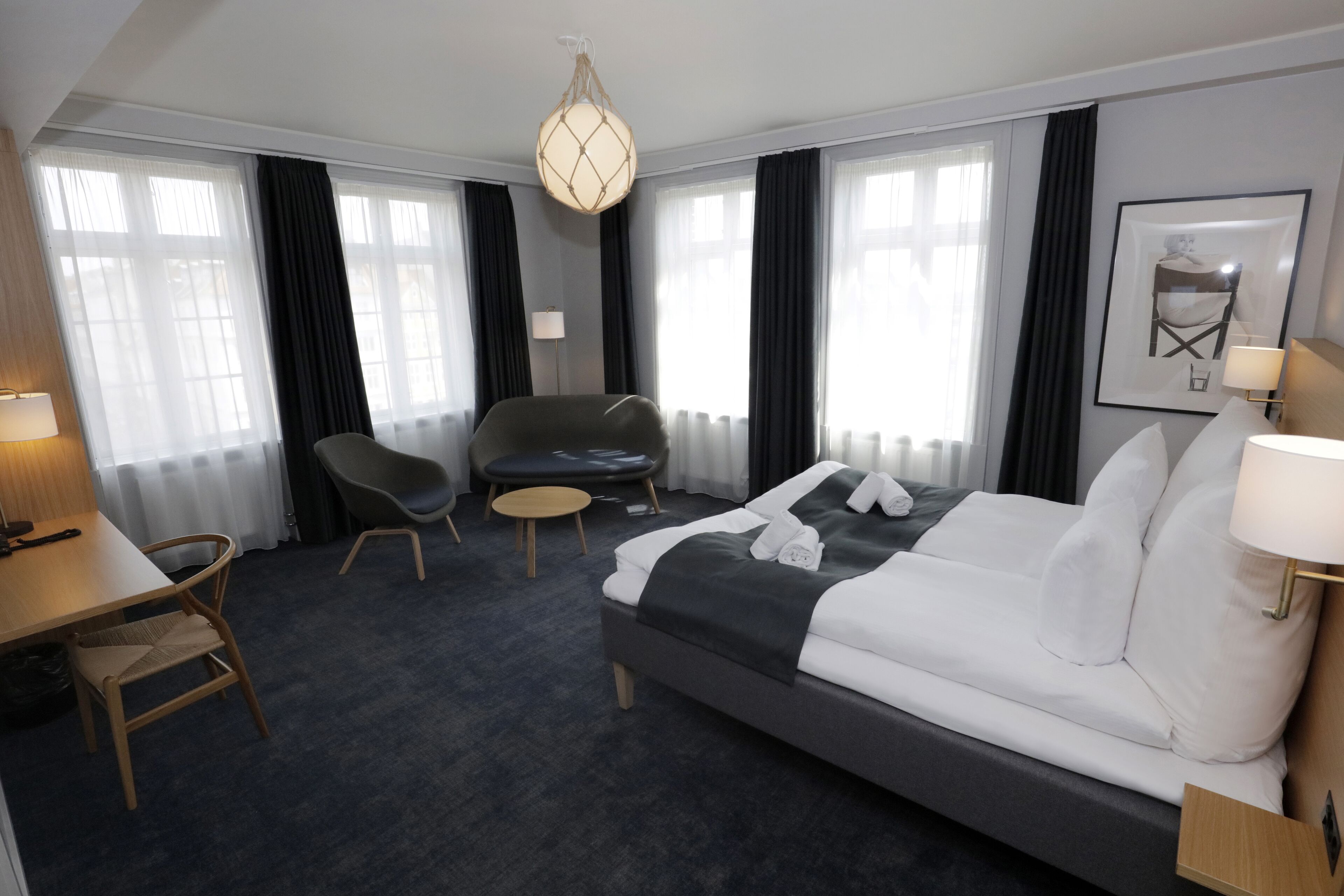 A hotel room with a bed, a desk, a chair, and a sofa.