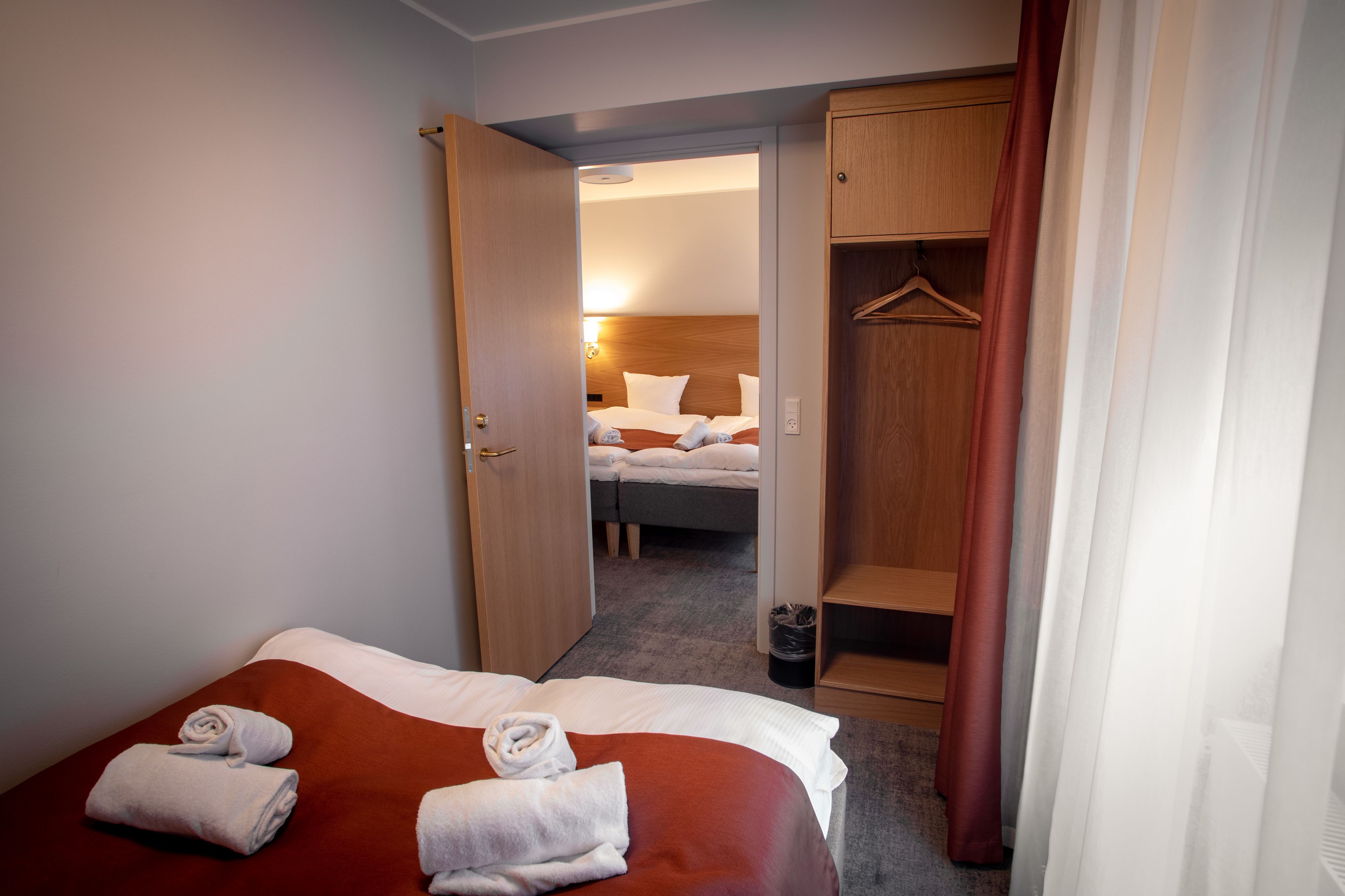 A hotel room with a bed, a wardrobe, and a bathroom visible through an open door.