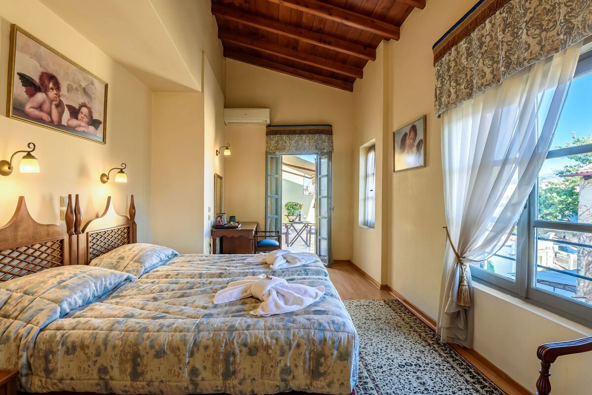 A bedroom with two beds, a wooden ceiling, a balcony, and a view of the outside.