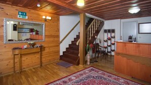 Un interior de madera con una escalera, un mostrador de recepción y un espejo en la pared.