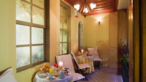 Un comedor con dos mesas preparadas para el desayuno, cada una con una vela, fruta y una tetera.