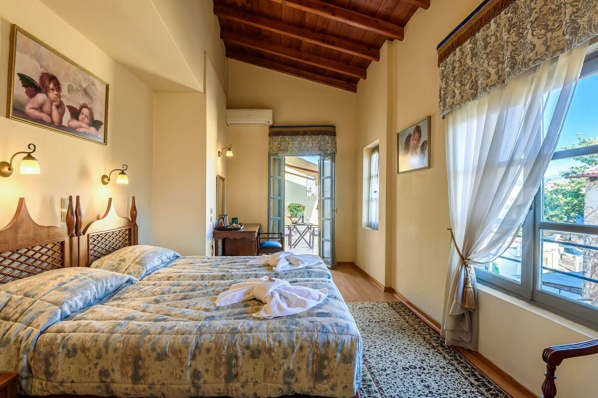 Un dormitorio con dos camas, techo de madera, un balcón y vistas al exterior.
