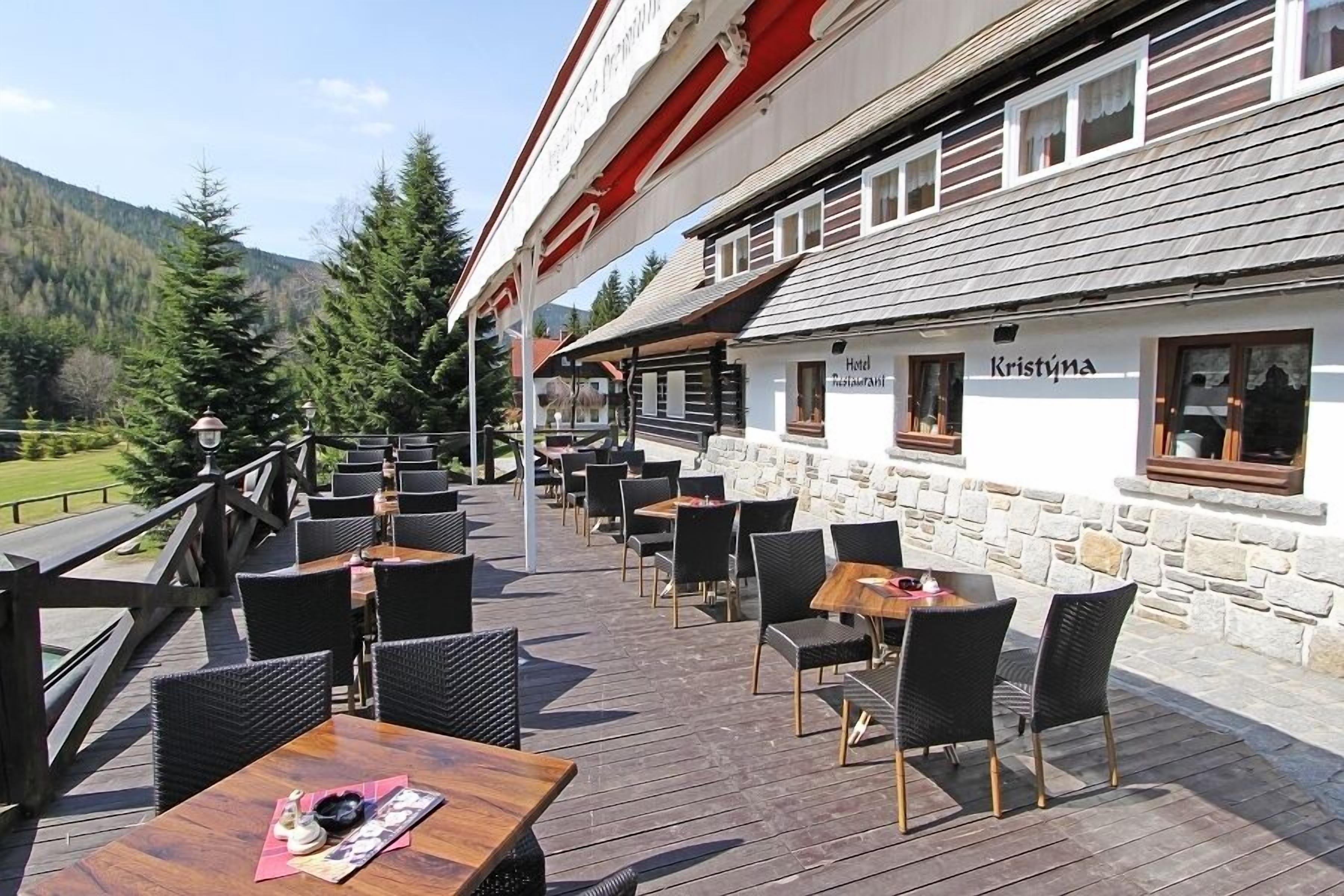 Ein Außenbereich mit Tischen und Stühlen, einer Holzterrasse und einer Steinmauer.