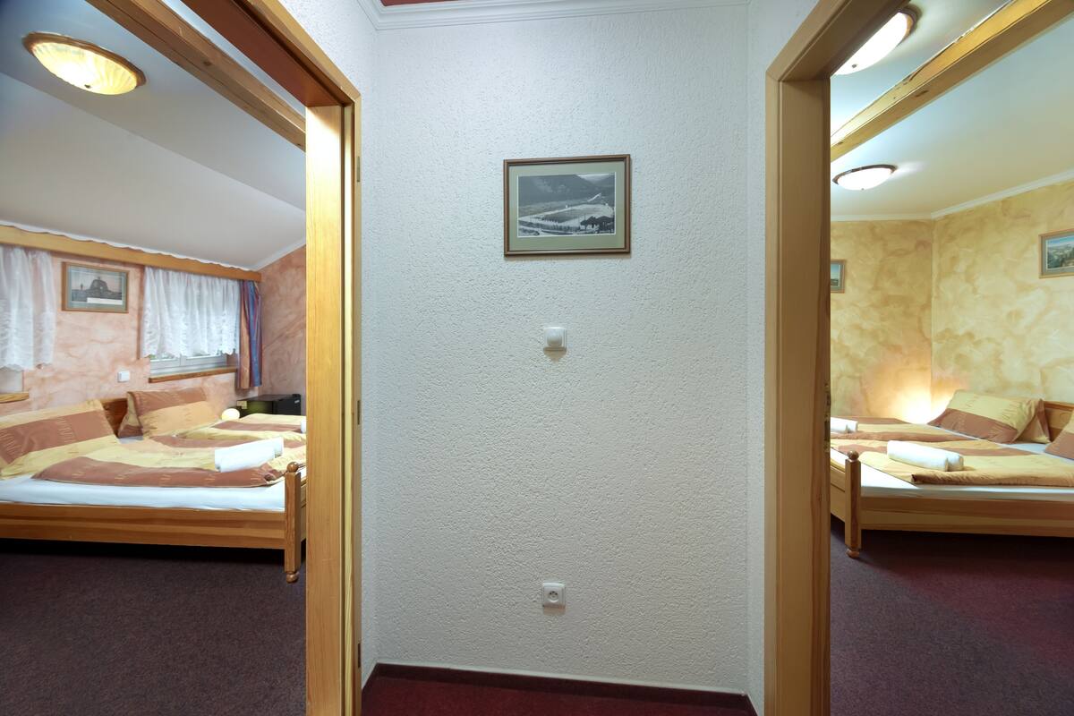 Una habitación con dos camas, un cuadro en la pared y un interruptor de luz.