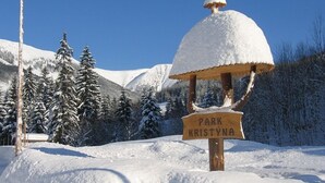 A snow-covered signpost with 'PARK KRISTYNA' written on it, surrounded by snow-laden trees and mountains. - Hotel Kristýna (Spindleruv Mlyn)