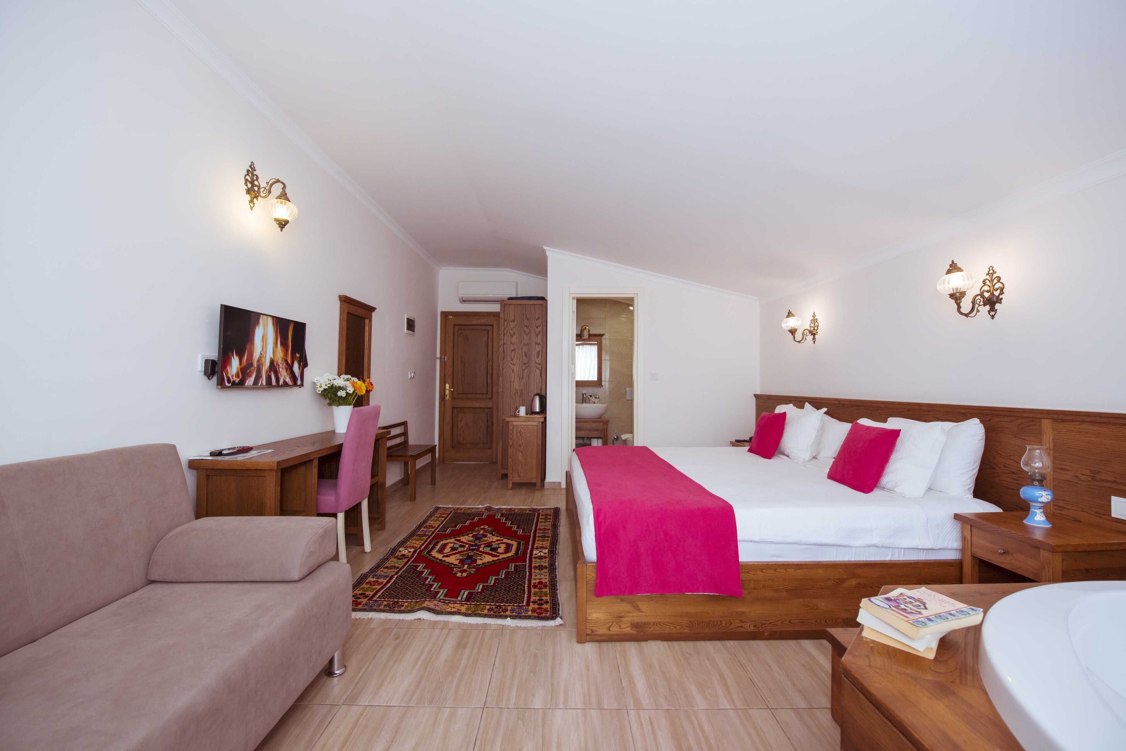 A hotel room with a bed, a sofa, a desk, and a chair.