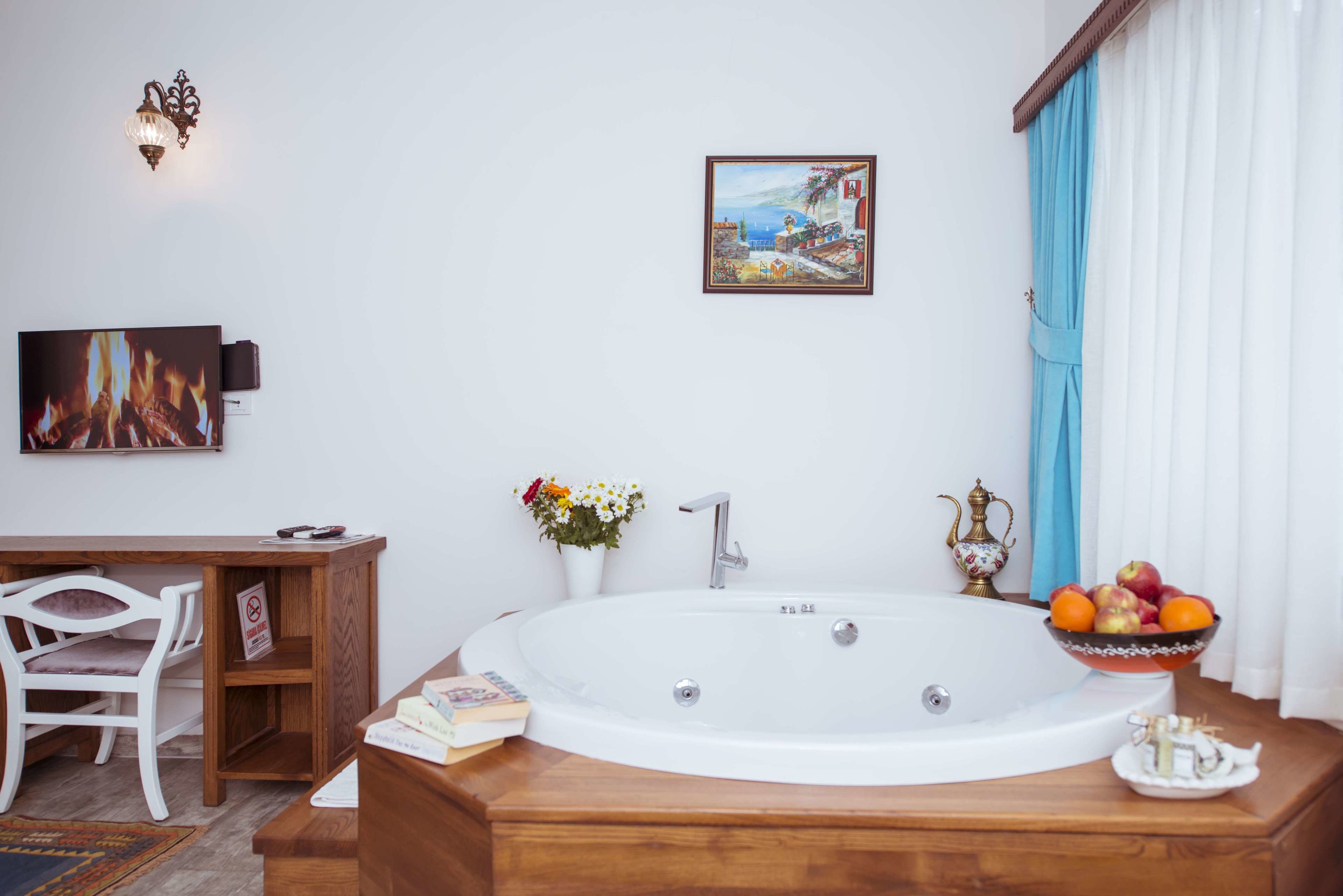 A bathroom with a bathtub, a wooden vanity, a chair, a framed picture, and a bowl of fruit.