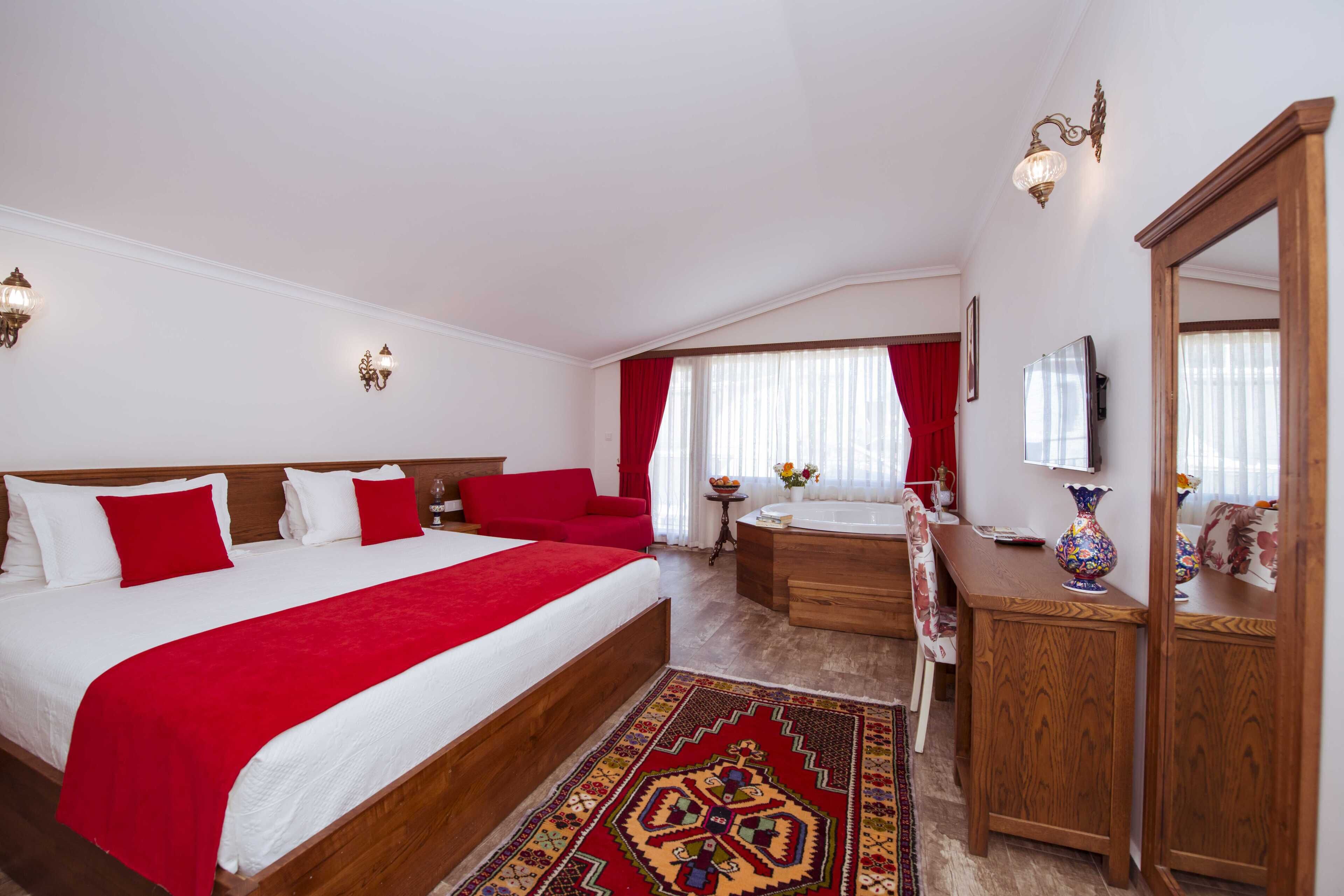 A hotel room with a large bed, a wooden dresser, a vanity, and a red carpet.