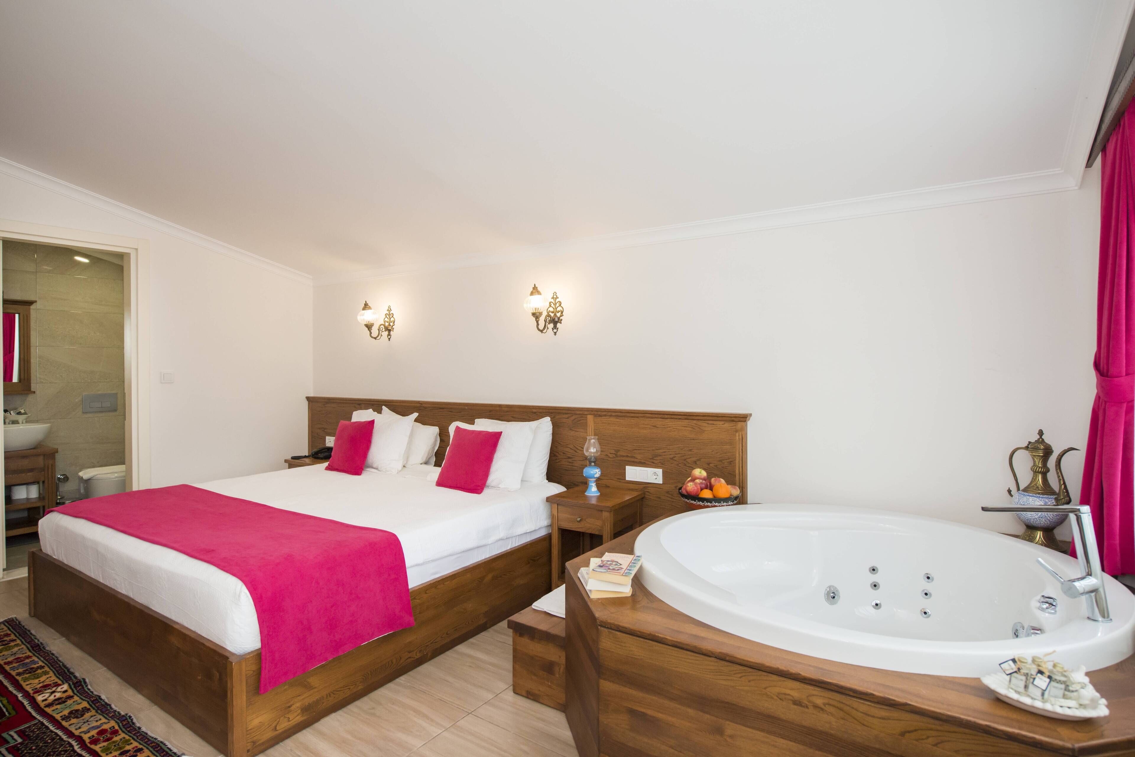 A bedroom with two beds, a large bathtub, and a wooden nightstand.