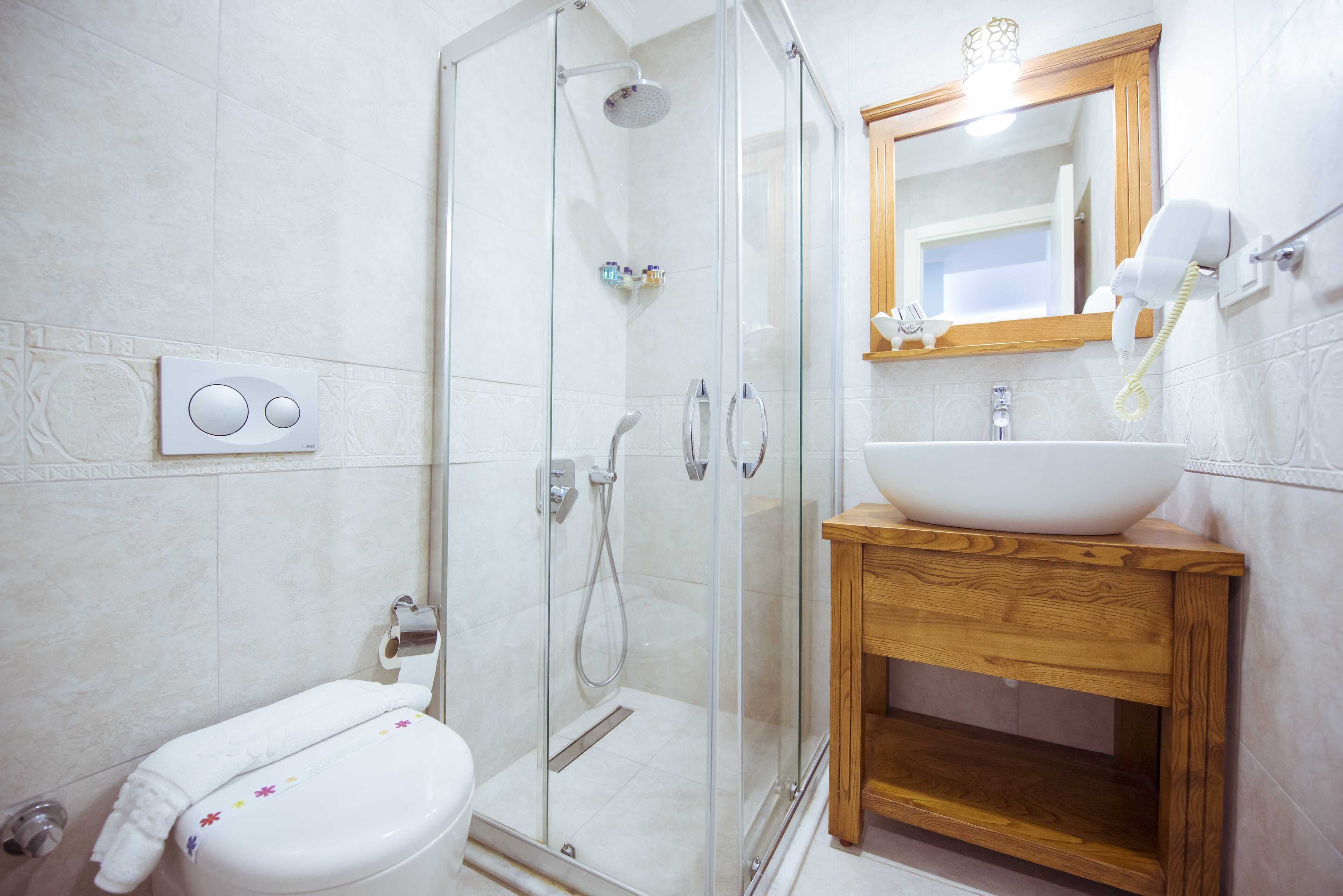 A modern bathroom with a glass shower enclosure, a wooden vanity, and a white toilet.