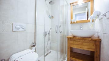 Un baño moderno con cabina de ducha de vidrio, tocador de madera y váter blanco.