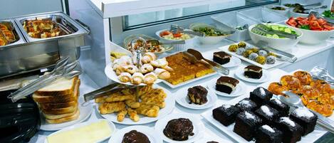 A buffet with various food items including bread, pastries, and desserts.