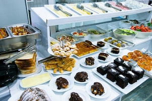 Een buffet met diverse gerechten, waaronder brood, gebak en desserts.