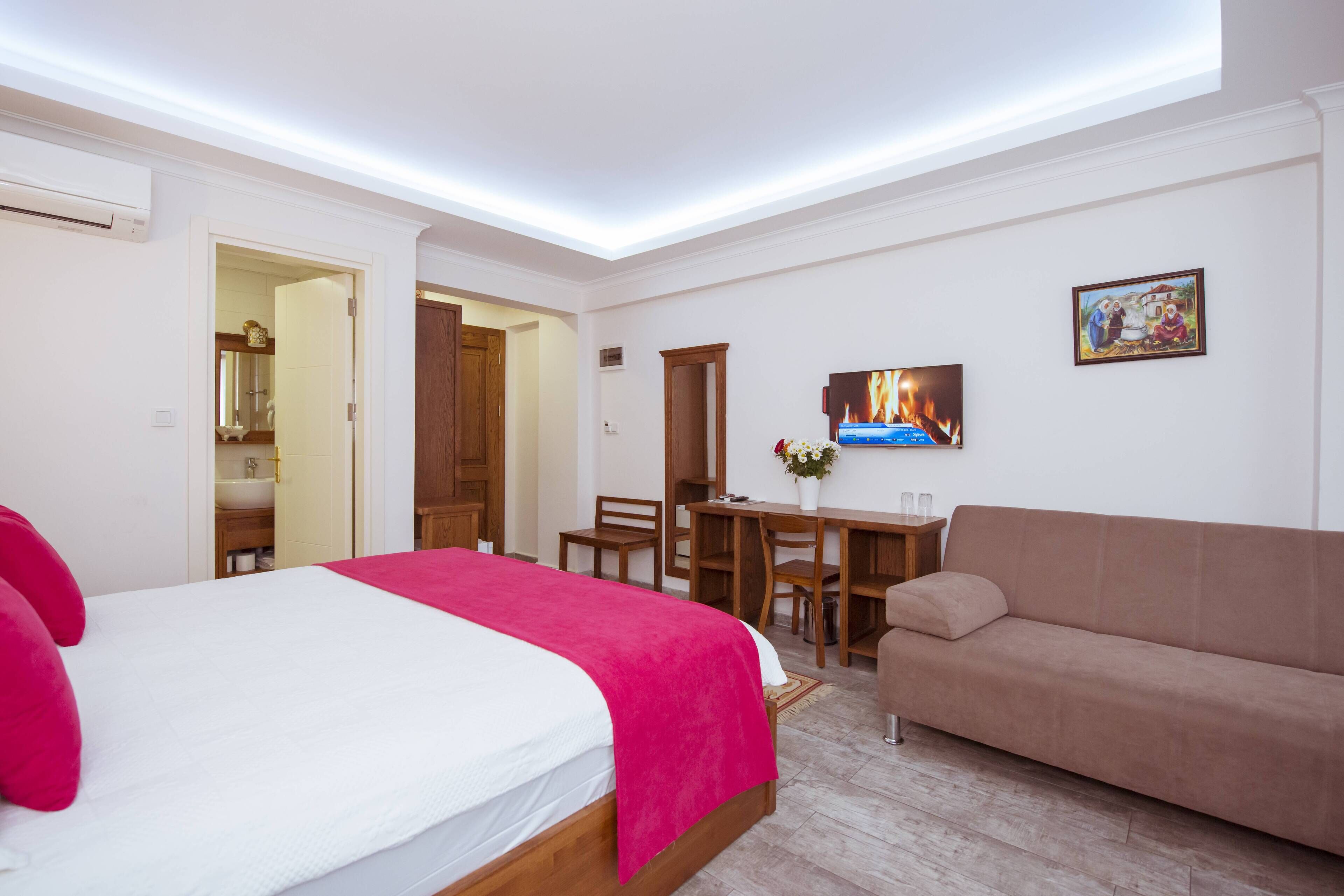 Une chambre d’hôtel avec un lit, un canapé, un bureau et une télévision.