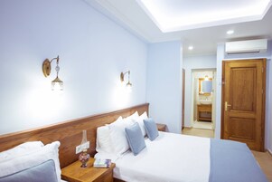 Een hotelkamer met een houten hoofdeinde, wit beddengoed en twee wandlampen.