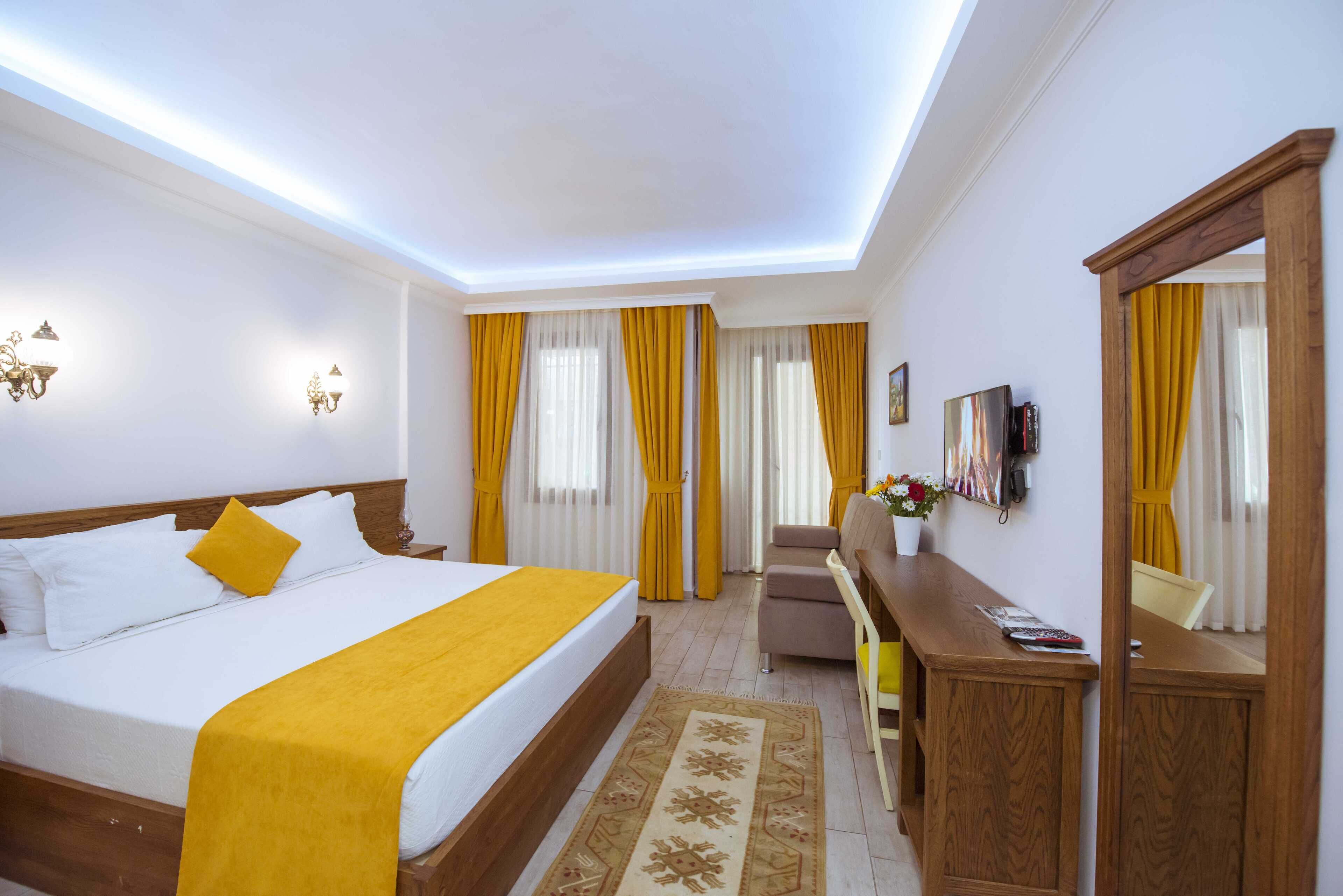 A hotel room with a large bed, a desk, a chair, and a television.