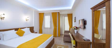 Una habitación de hotel con una cama grande, un escritorio, una silla y un televisor.