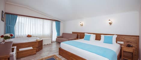 Un dormitorio amplio con una cama grande, cabecera de madera, una zona de estar con una silla, una mesita pequeña, una bañera y una ventana con cortinas.