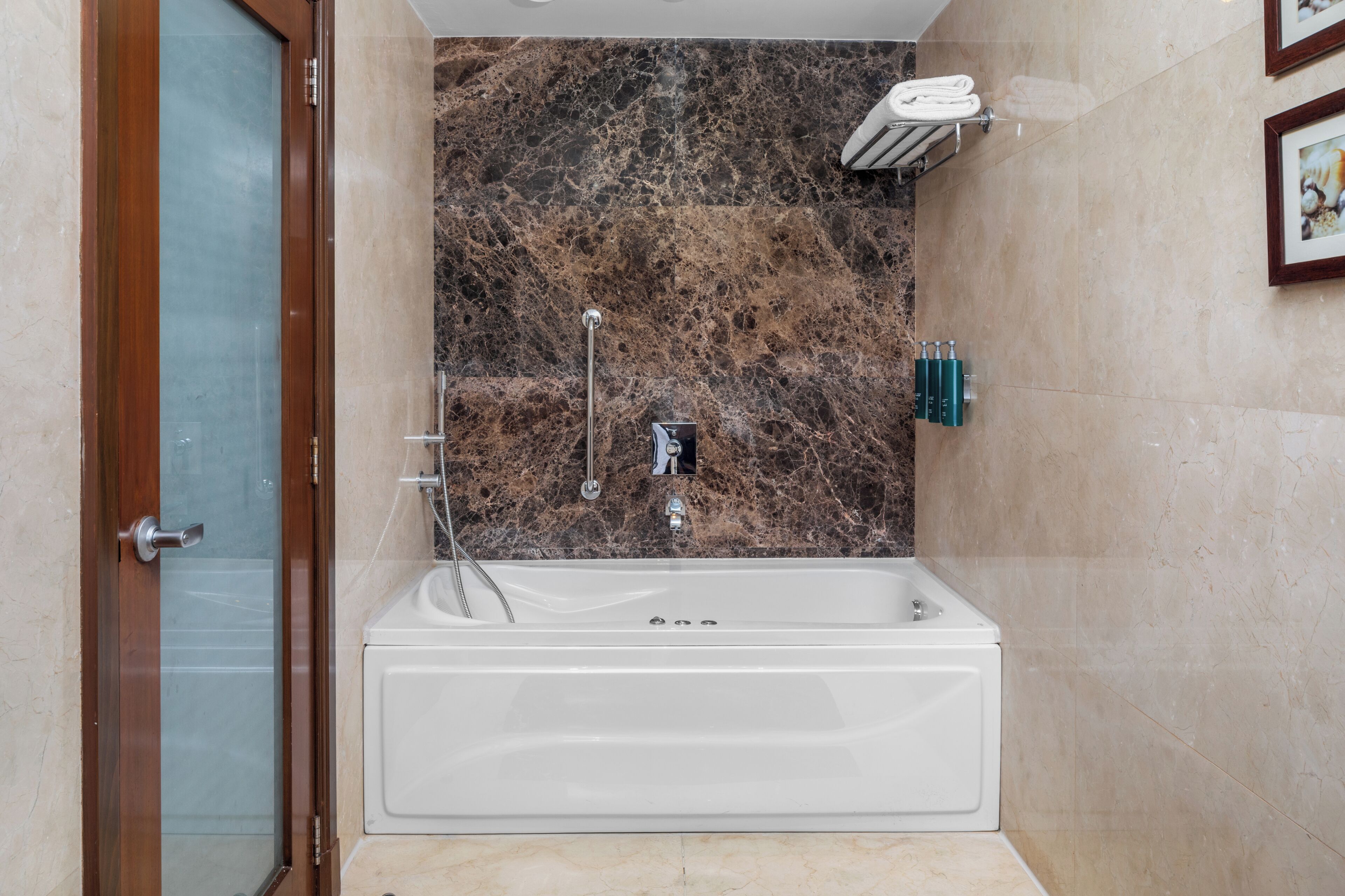 Un baño moderno con una bañera independiente, paredes de mármol, cabina de ducha de vidrio y un perchero para toallas.