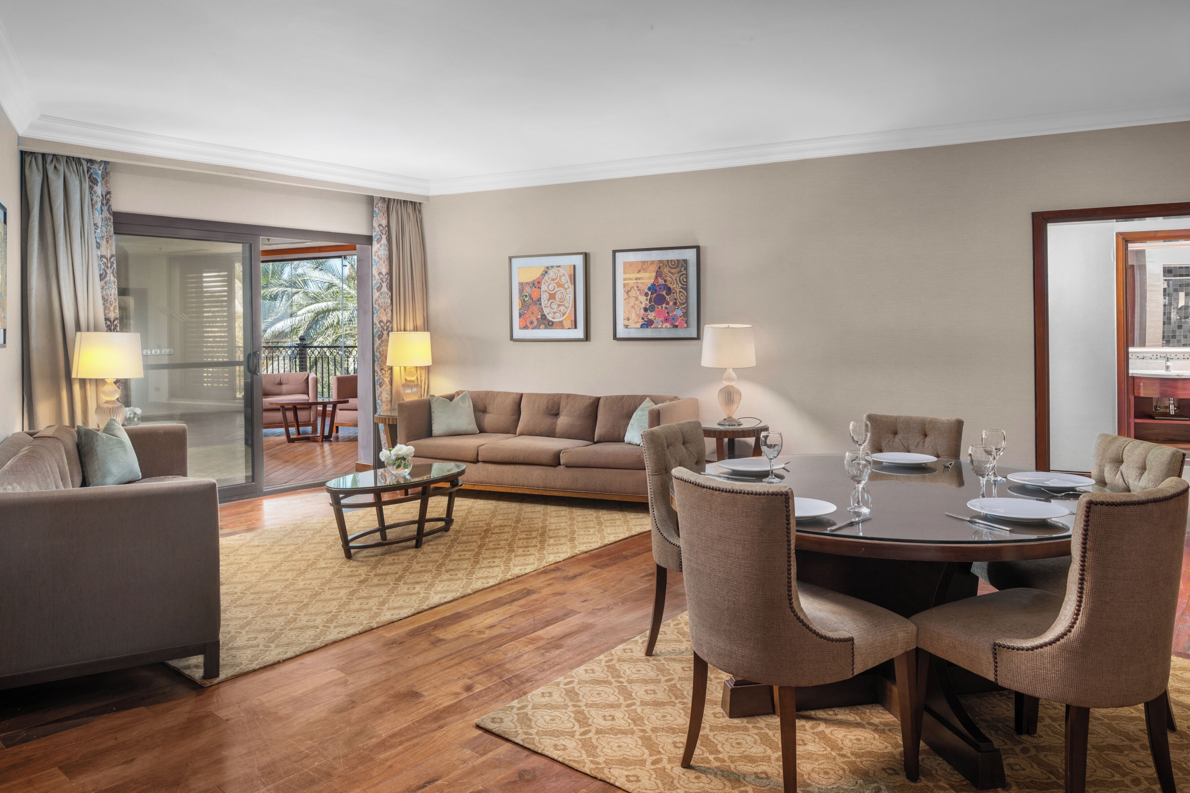 Ein Wohnzimmer mit Sofa, Couchtisch, Esstisch mit Stühlen und Bildern an der Wand.
