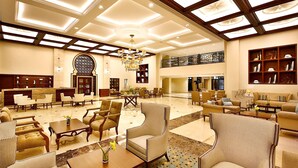 A spacious lobby with high ceilings, chandeliers, and a variety of seating arrangements including sofas and armchairs.