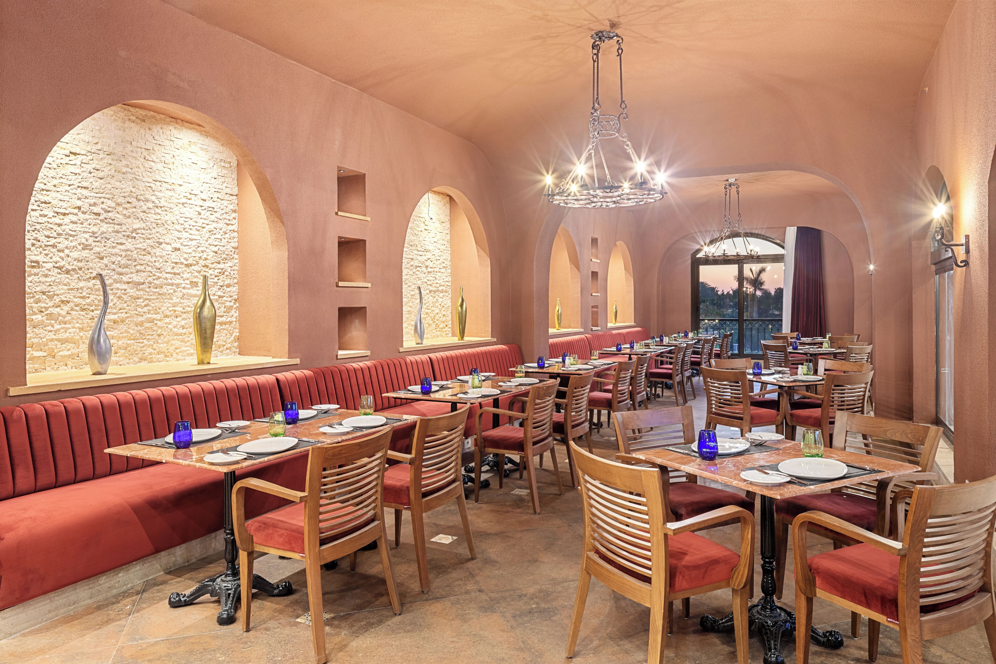 Un restaurant avec des banquettes rembourrées de tissu rouge, des tables et des chaises en bois.