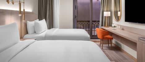 A hotel room with two beds, a desk, a chair, a television, and a balcony with curtains.