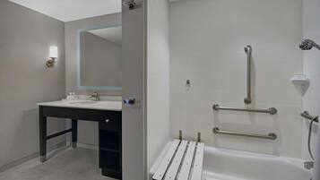 Un baño moderno con lavamanos, espejo y zona de ducha.