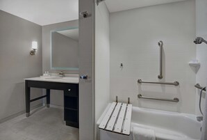 Un baño moderno con lavamanos, espejo y zona de ducha.