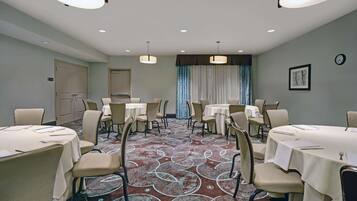 Un salón de conferencias con mesas redondas, sillas y una alfombra estampada.