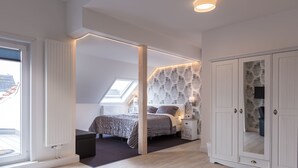 Ein Schlafzimmer mit Bett, Schrank, Nachttisch, Heizkörper und einem Oberlicht.