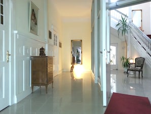 A spacious hallway with a wooden cabinet, a mirror, and a staircase leading to an upper floor. - Hotel Atlantic Travemünde (Lübeck)