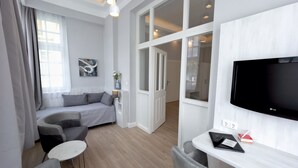 Ein modernes Wohnzimmer mit grauem Sofa, einem kleinen runden Tisch und einem flachbildfernseher an der Wand.