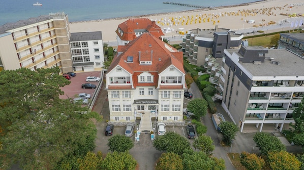 A hotel with a central courtyard, surrounded by modern buildings and a beach in the background. - Hotel Atlantic Travemünde (Lübeck)