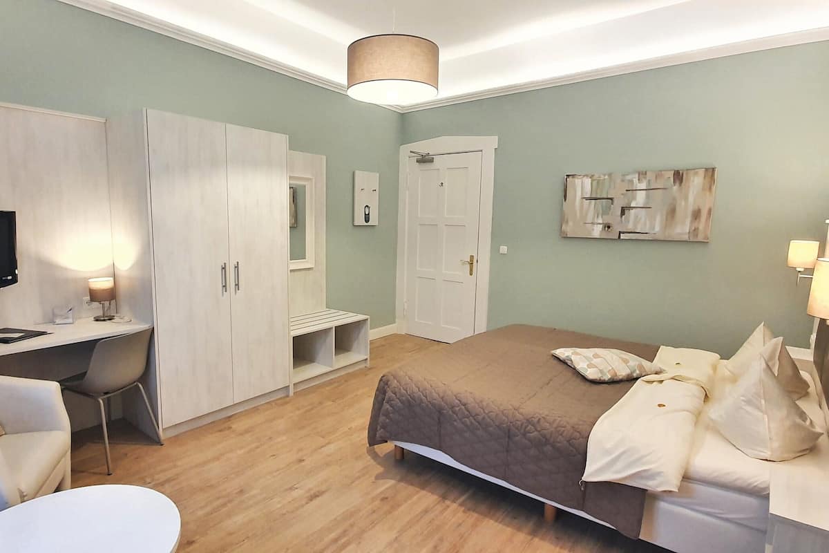 Ein Schlafzimmer mit Bett, Schreibtisch, Stuhl, Fernseher und Kleiderschrank.