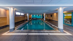 Une piscine intérieure avec un sol carrelé, des murs en bois et un mur d’accent bleu.