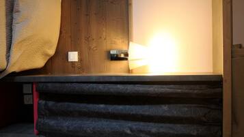 A room with a bed, a wooden door, and a wall-mounted light fixture.