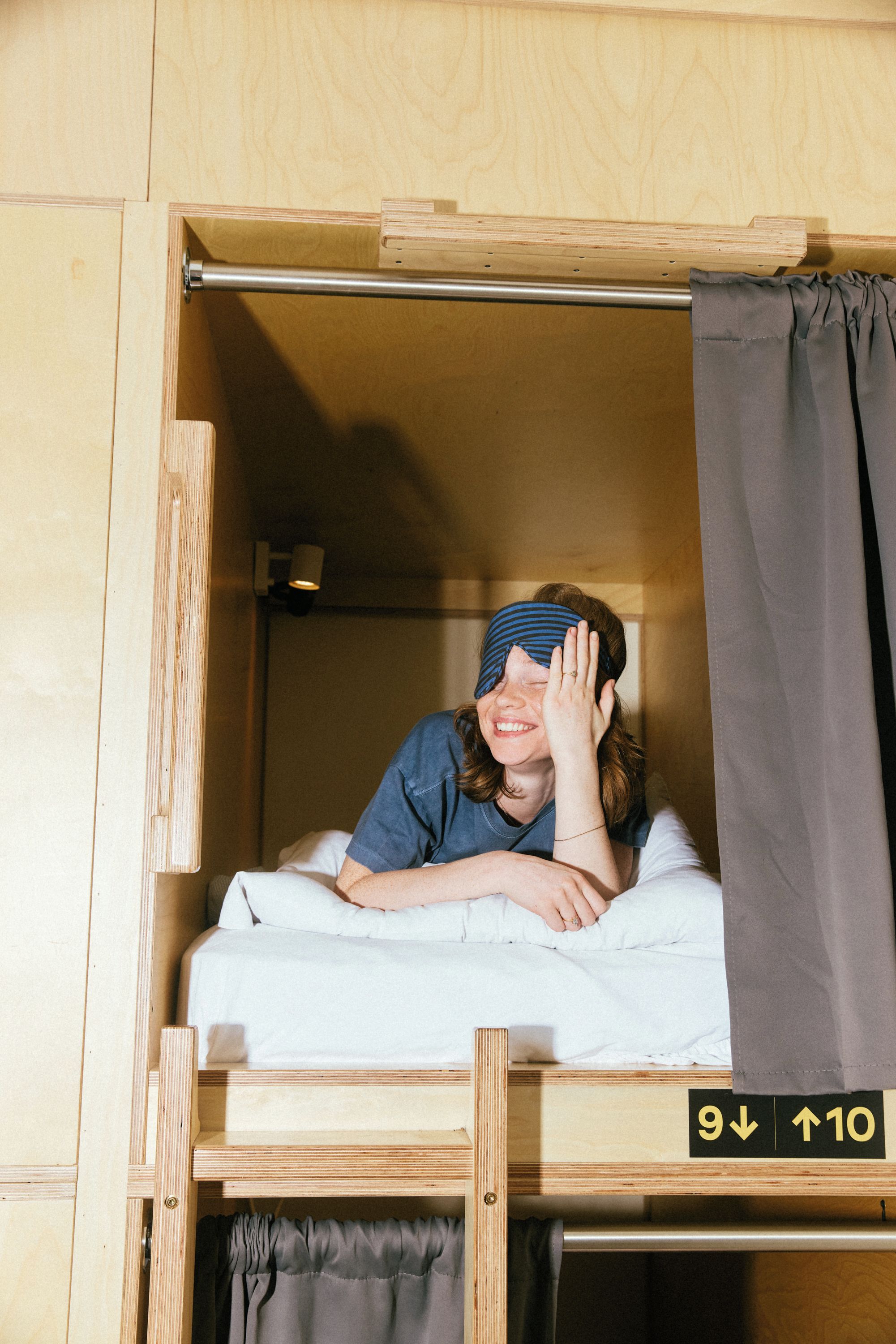A small, enclosed sleeping area with a wooden frame, a mattress, and a curtain.