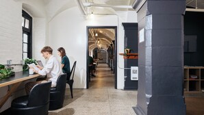 A modern interior with a long corridor, black chairs, a wooden table, and a black pillar. - Saintlo Ottawa Jail Hostel (Ottawa)