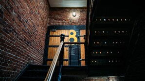 A brick wall with a wooden door marked with the number 8, a metal staircase, and a skylight above. - Saintlo Ottawa Jail Hostel (Ottawa)